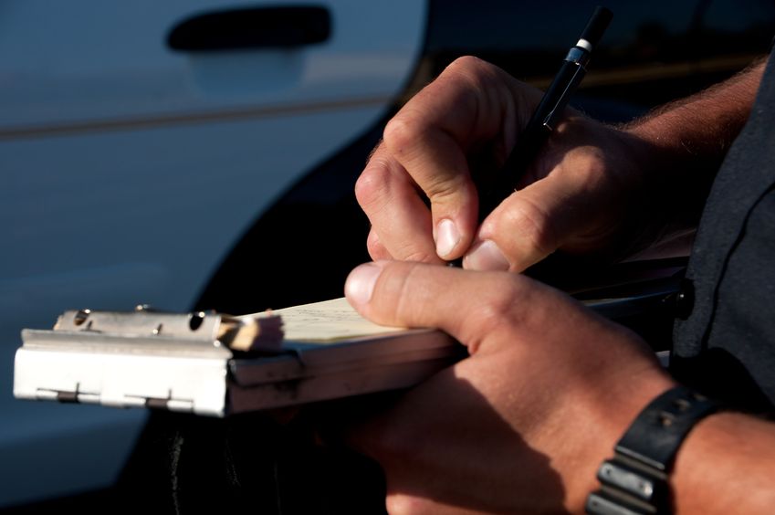 a close up of a police officer writing a traffic ticket.